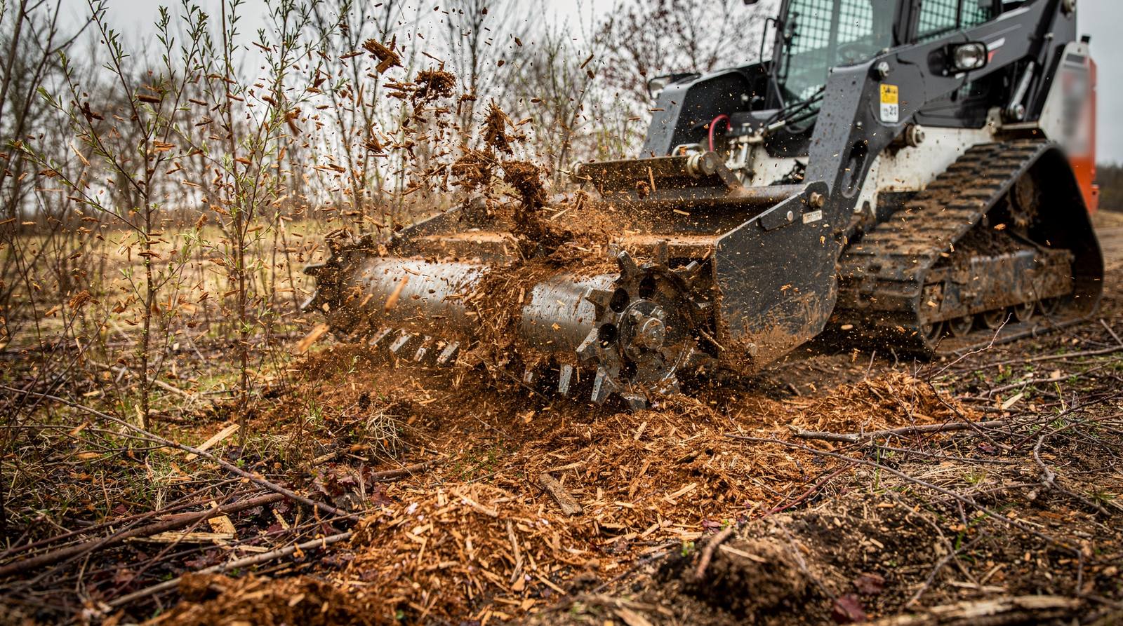 Forestry mulching head on a compact track loader grinding brush and saplings into mulch