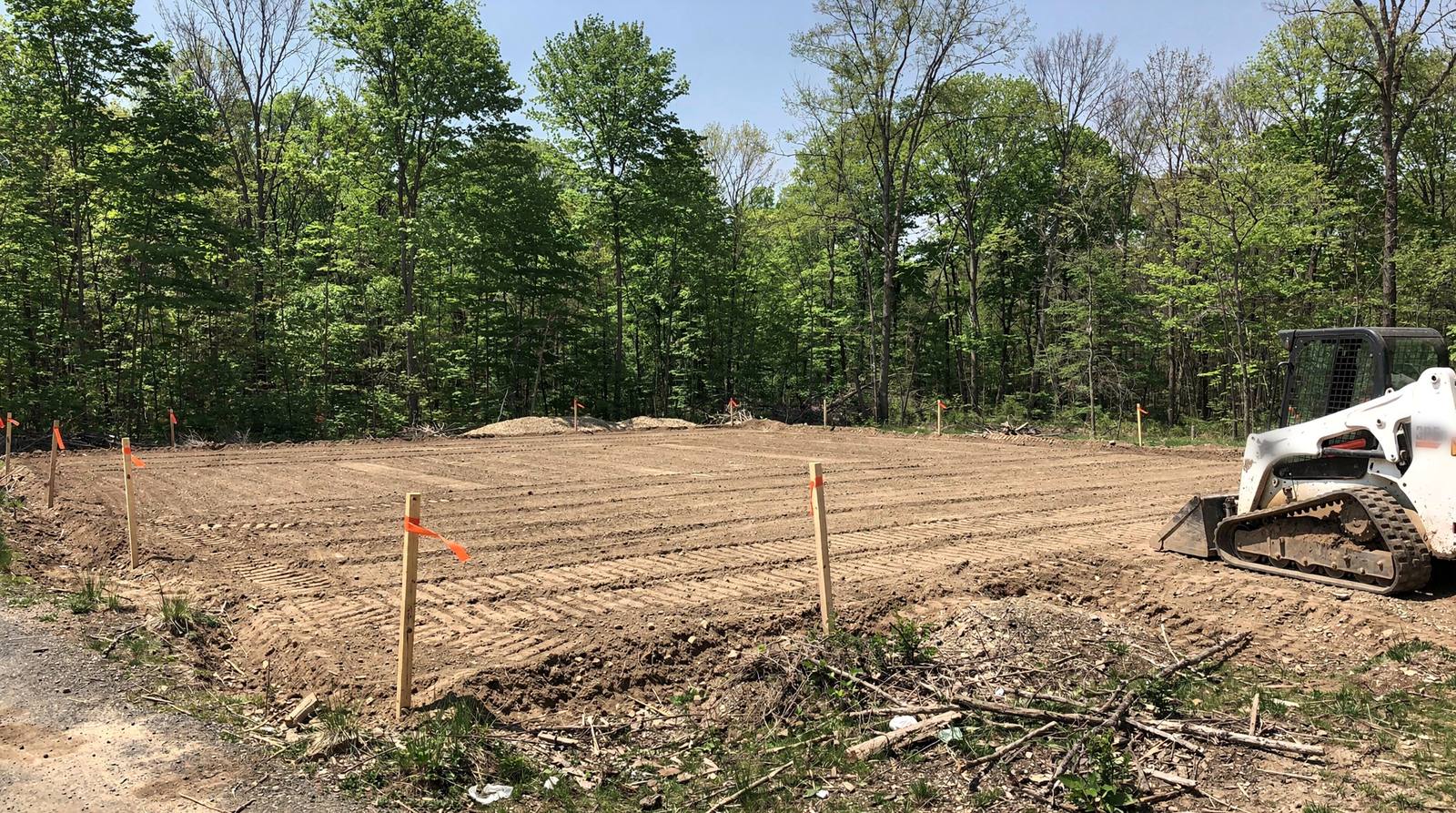 Cleared and rough-graded building pad staked out on a wooded lot